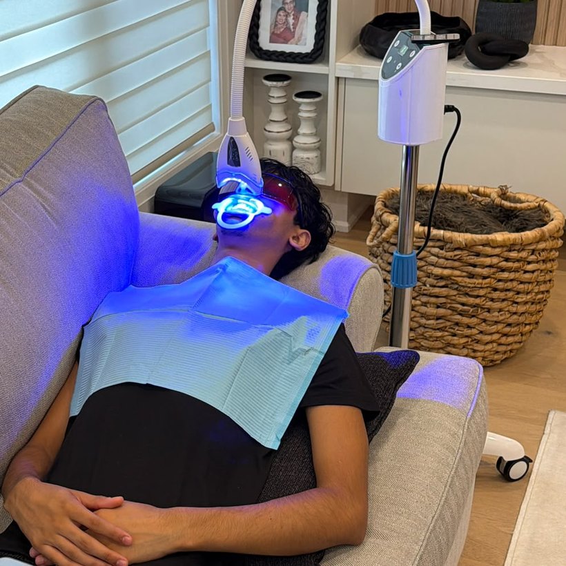 A client relaxing on a sofa during a whitening session at home